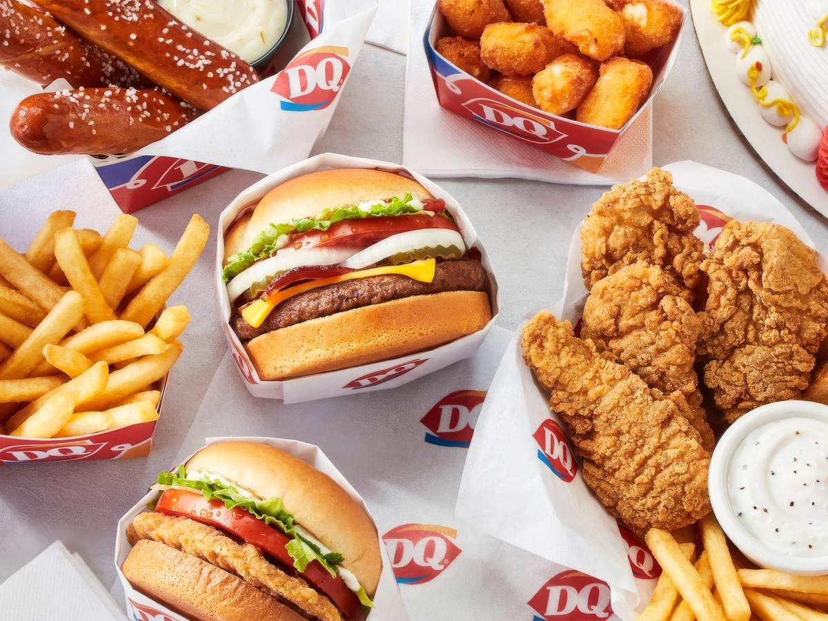 Food spread with burgers, chicken strips, fries, pretzel sticks, and dessert