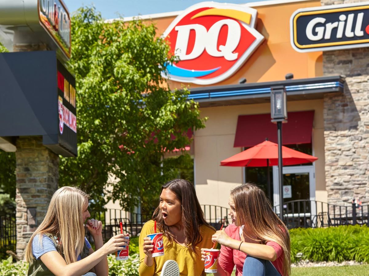 Three people enjoying Dairy Queen treats outside the restaurant