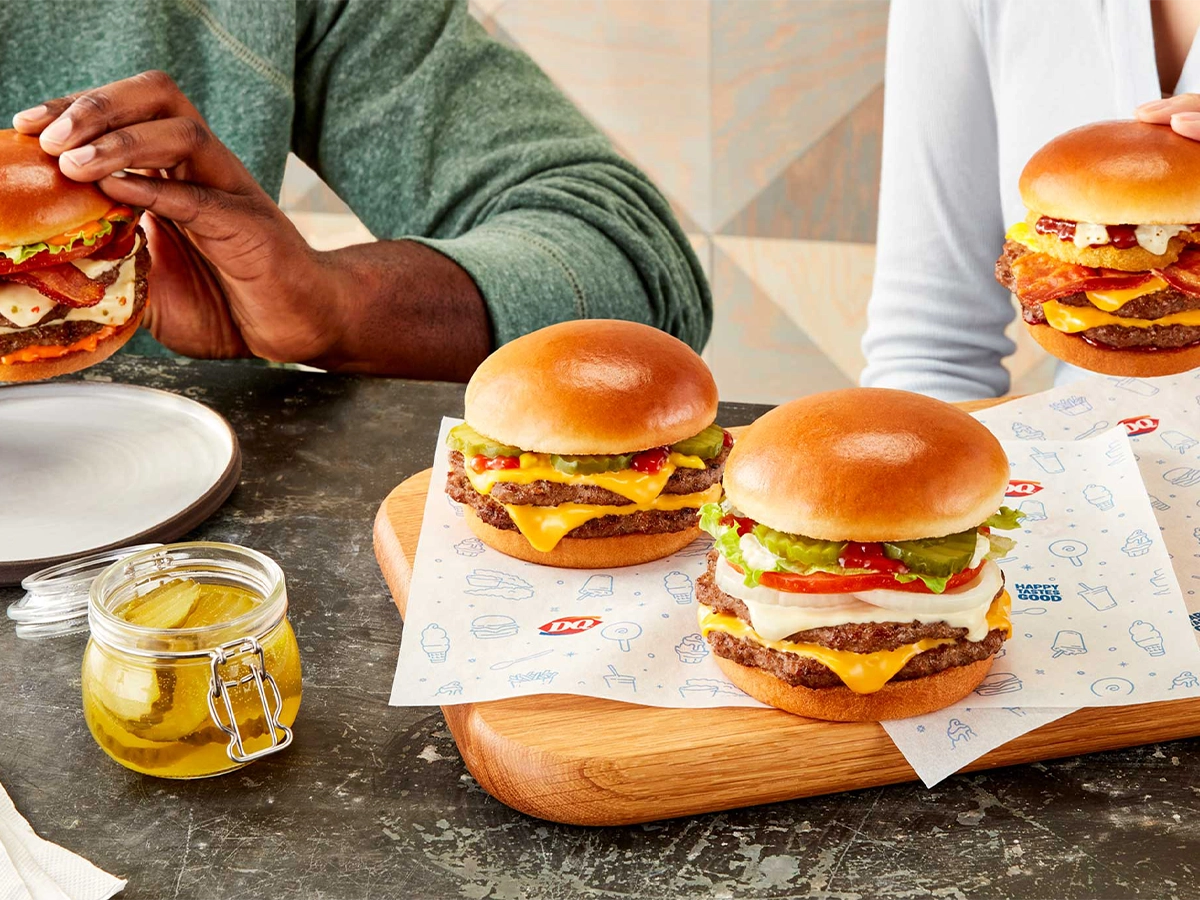 Three stacked burgers on a serving board